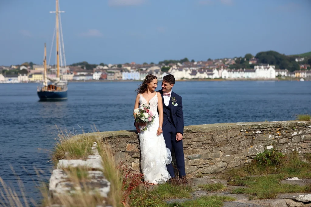 Seaside wedding photo of Brandon and Amy with a boat in the background.