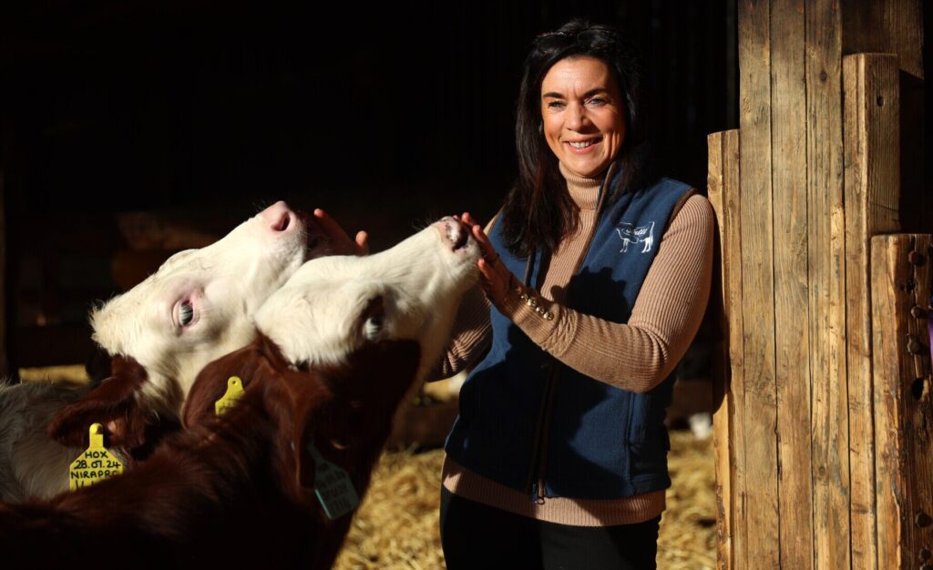 A portrait of a farmer with her cows in a barn.