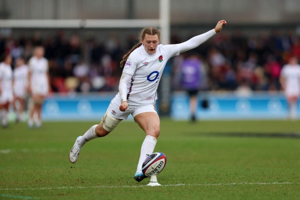 An England rugby player executing a kick on the field during a match.
