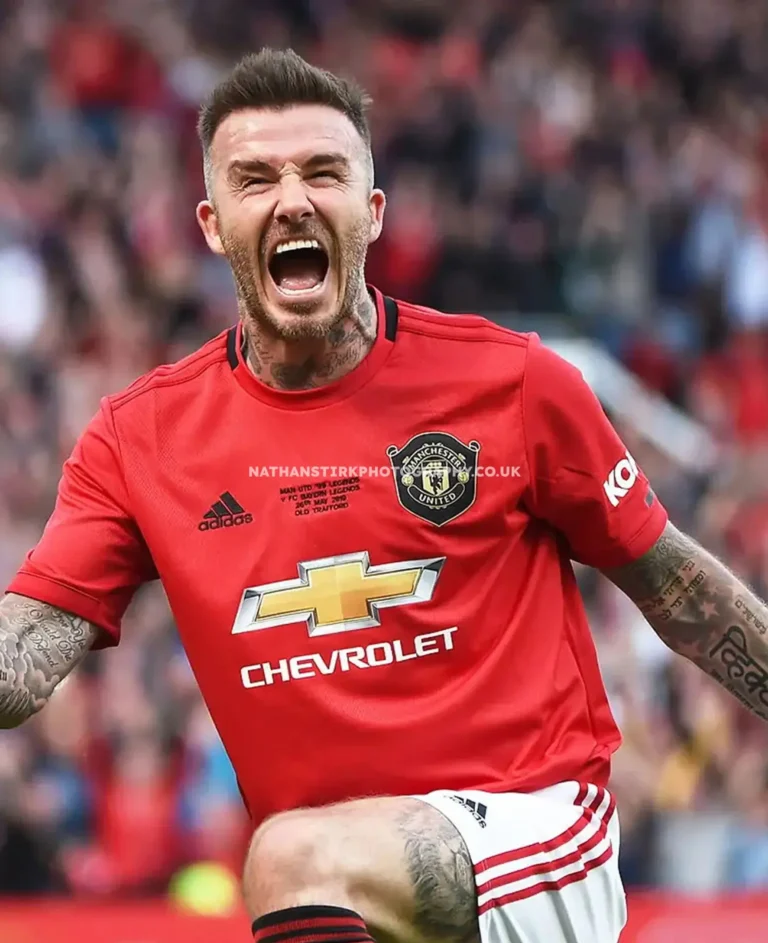 David Beckham celebrating a goal in Manchester United's iconic red jersey.