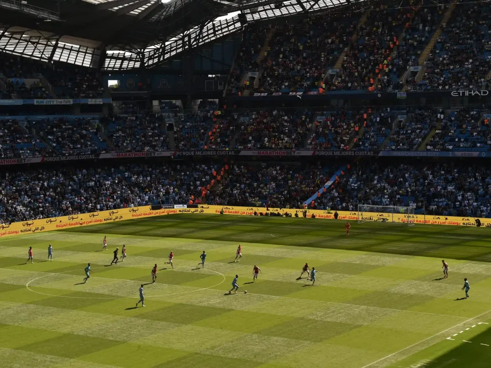 An exciting football match unfolding at Etihad Stadium with fans cheering in the stands.