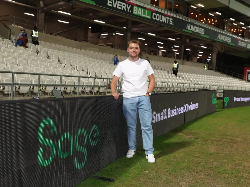 A man posing at a sporting event with empty stands in the background.