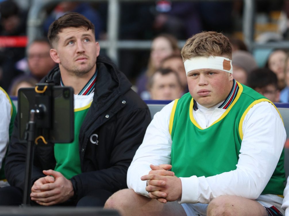 Intense moments captured of rugby players on the bench, showcasing their emotions during a match.